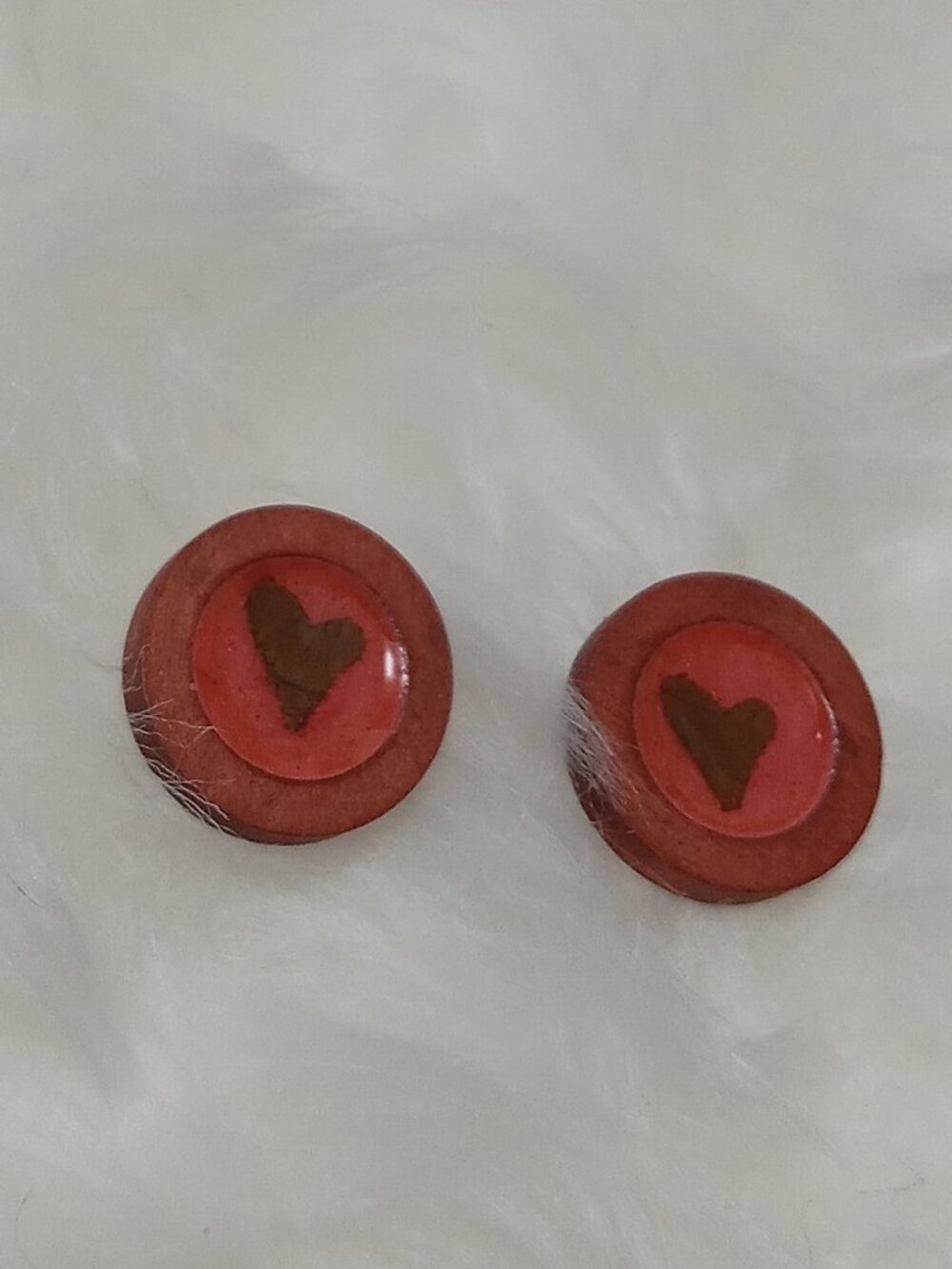 Handmade earrings on a wooden base with a piece of punched-out tree leaf